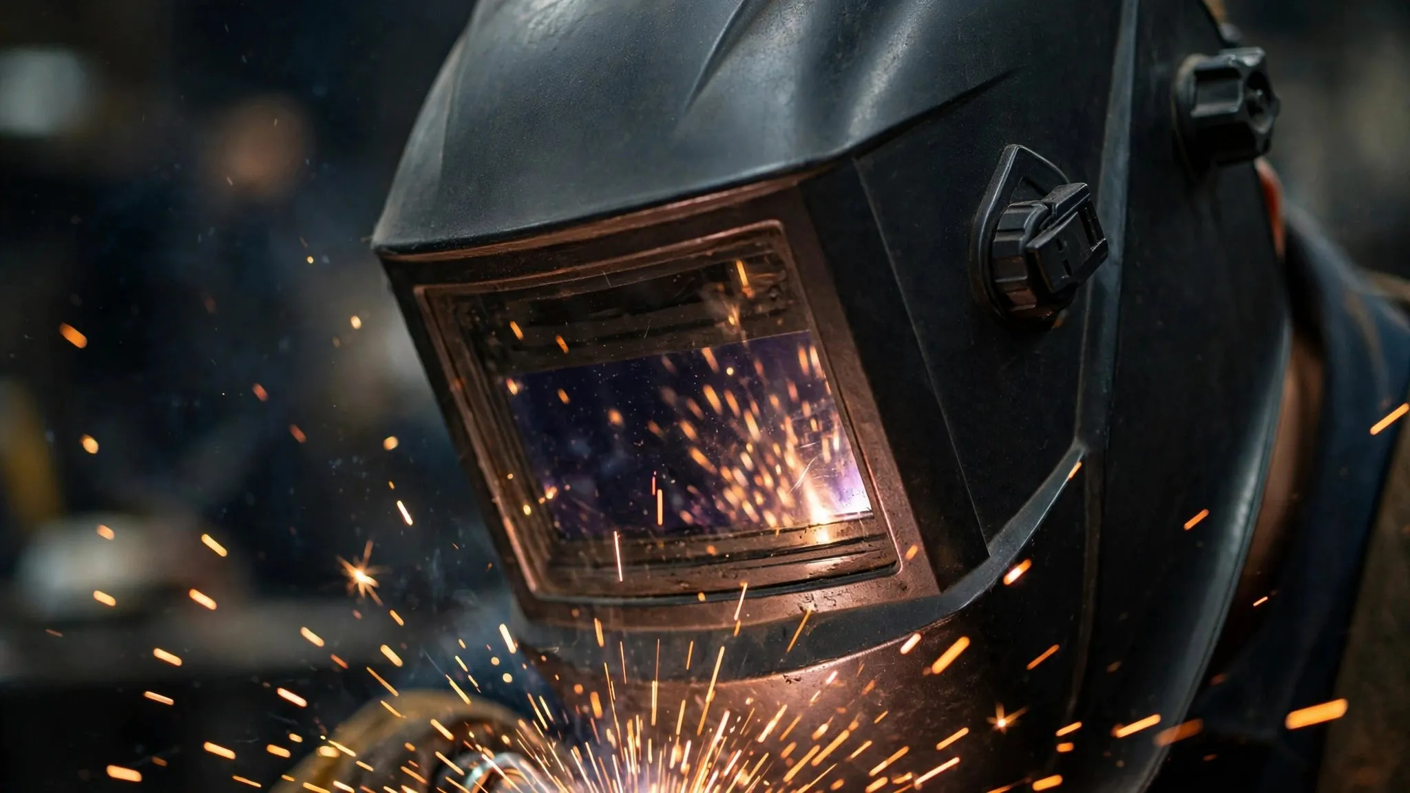 Welder in a protective helmet with sparks flying from the weld